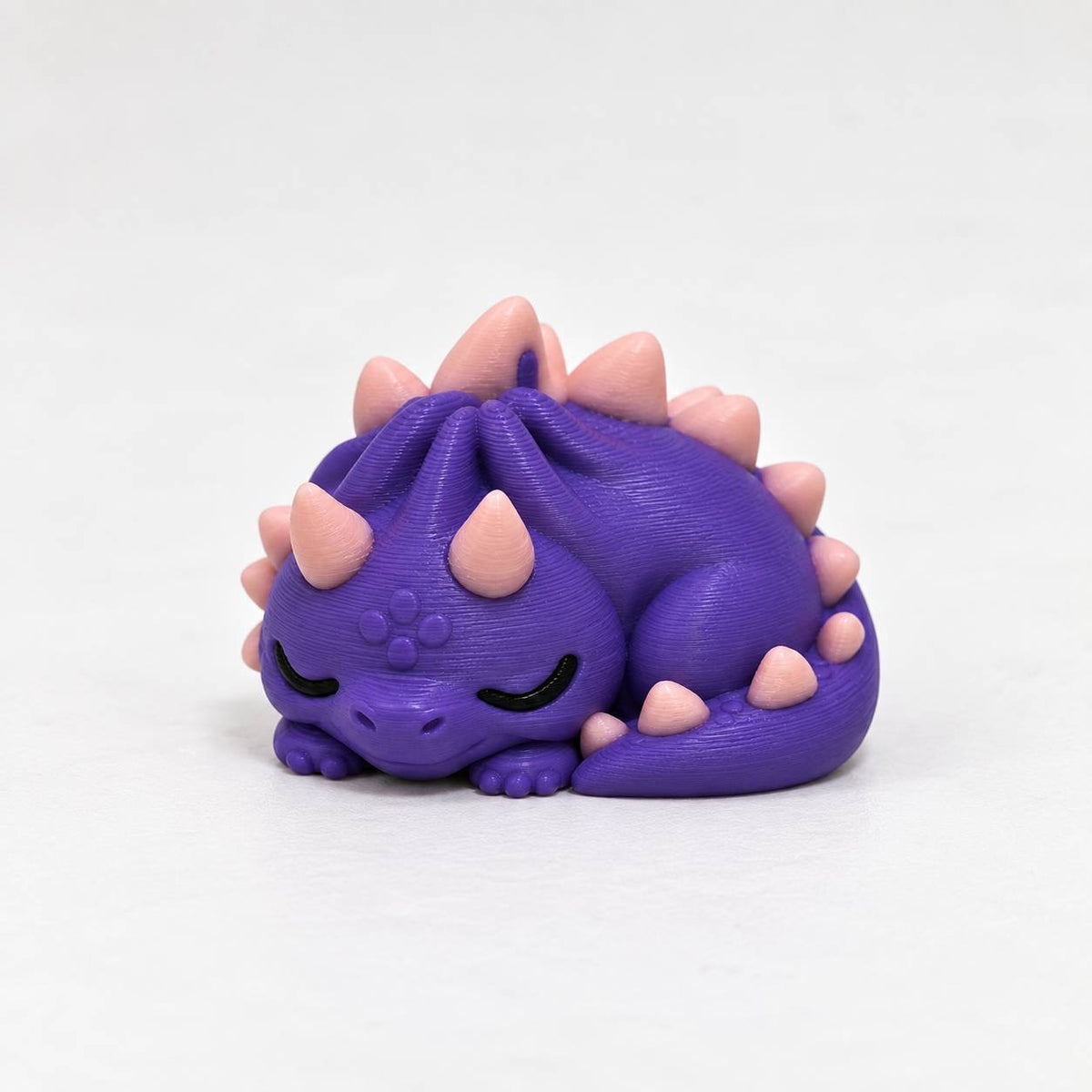 Purple sleeping dragon 3D printed bead with pink spikes and curled tail