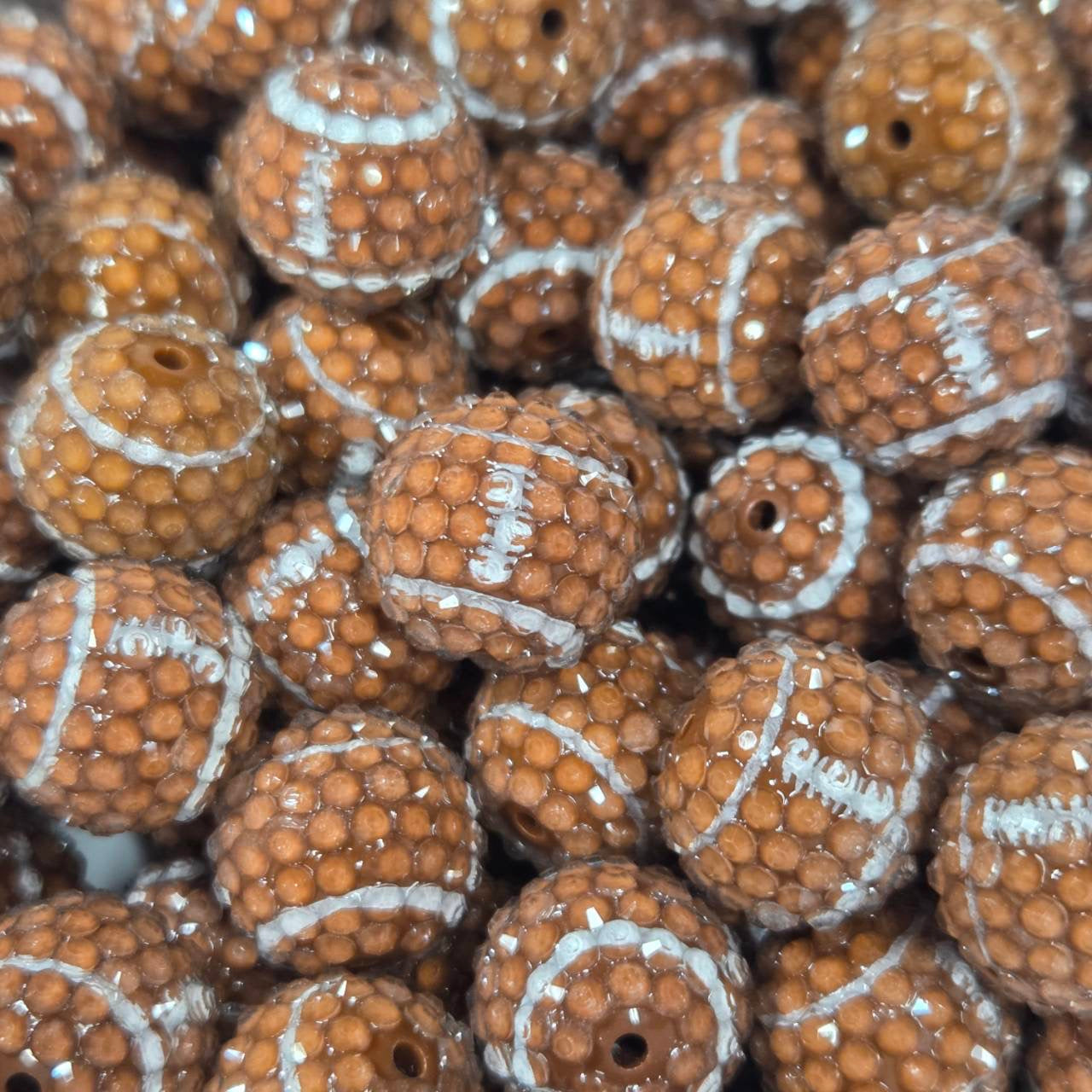 Brown football-shaped acrylic bead with textured detailing and white laces for sports-themed craft projects