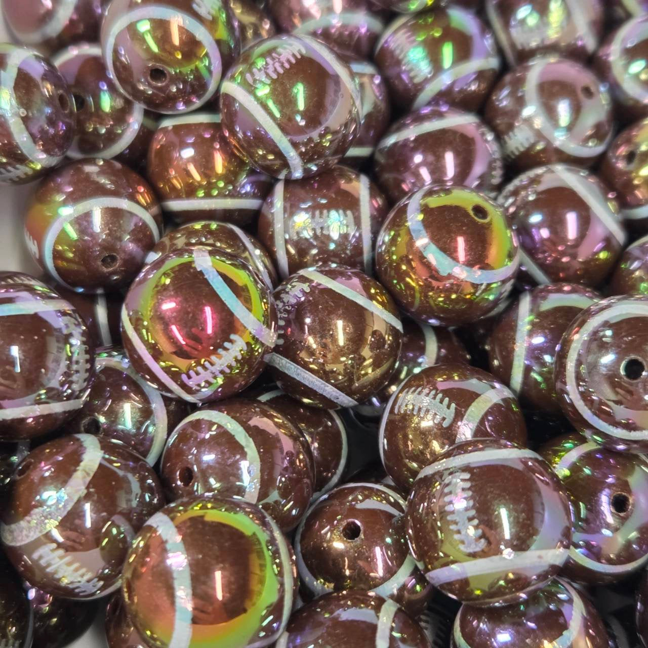 Iridescent football-shaped acrylic bead with white laces and a shimmering finish for football-themed craft projects.
