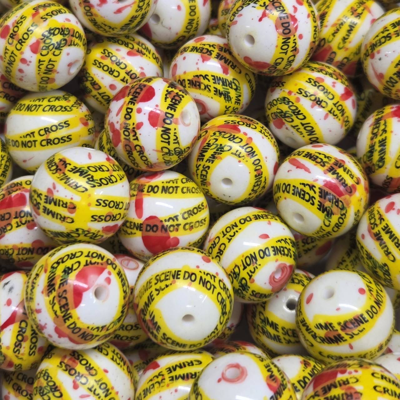White 20mm printed acrylic bead wrapped with yellow "Crime Scene Do Not Cross" tape and red splatter details for Halloween-themed craft projects.