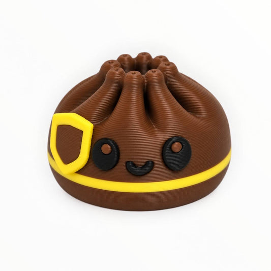 Brownie Express 3D printed dumpling bead featuring a chocolate-brown body, bright yellow stripe, yellow shield-inspired accent, and adorable black smiling face.