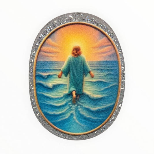 Walking in Faith oval acrylic focal bead featuring Jesus walking on blue ocean waves toward a golden sunset, surrounded by a sparkling silver glitter border.